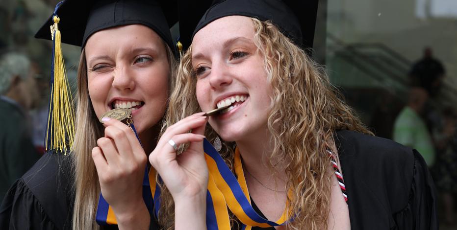 two students posing with their commencement medals